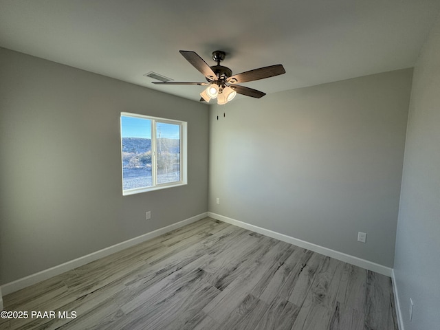 empty room featuring a ceiling fan, light wood-style flooring, and baseboards