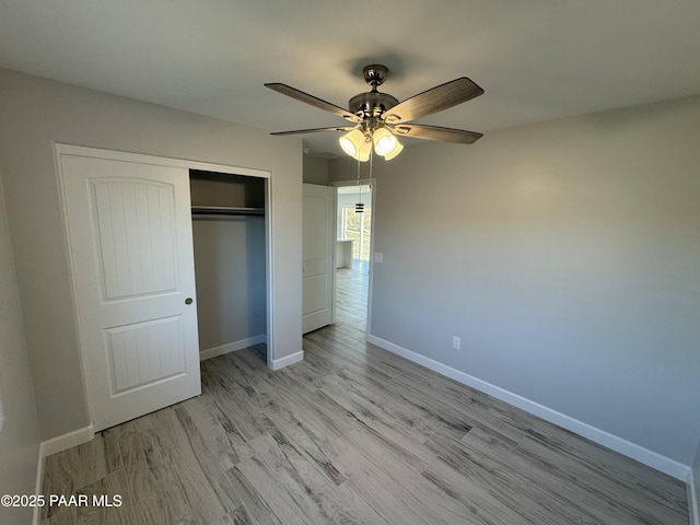 unfurnished bedroom with a closet, wood finished floors, a ceiling fan, and baseboards