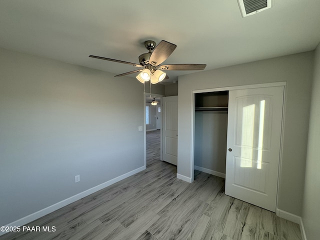 unfurnished bedroom featuring a closet, visible vents, light wood-style flooring, ceiling fan, and baseboards