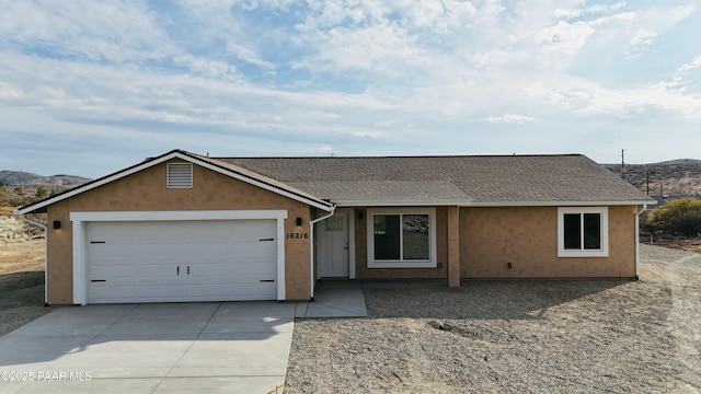 ranch-style home featuring a garage, concrete driveway, roof with shingles, and stucco siding