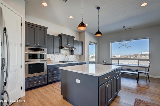 kitchen with hanging light fixtures, appliances with stainless steel finishes, a center island, and backsplash