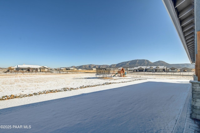 yard covered in snow featuring a playground and a mountain view