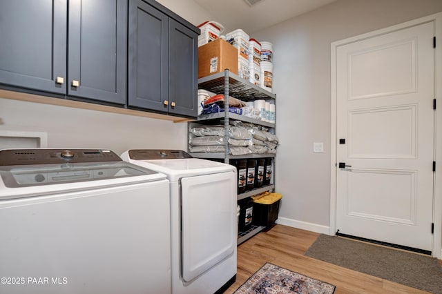 laundry area featuring cabinets, washing machine and clothes dryer, and light hardwood / wood-style floors