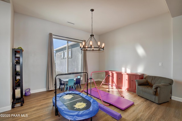 playroom with hardwood / wood-style flooring and a notable chandelier