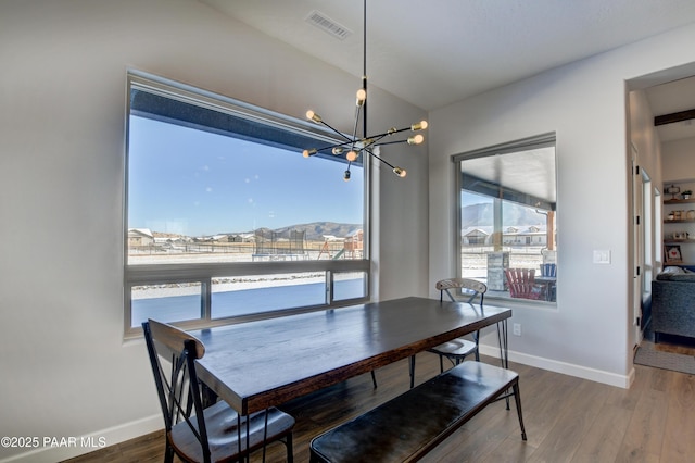 dining room featuring a water view, wood-type flooring, and a notable chandelier