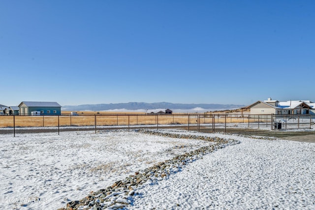 yard covered in snow with a mountain view and a rural view