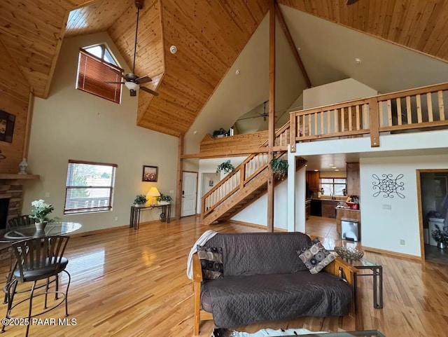 living room with a healthy amount of sunlight, stairway, wood finished floors, and a stone fireplace