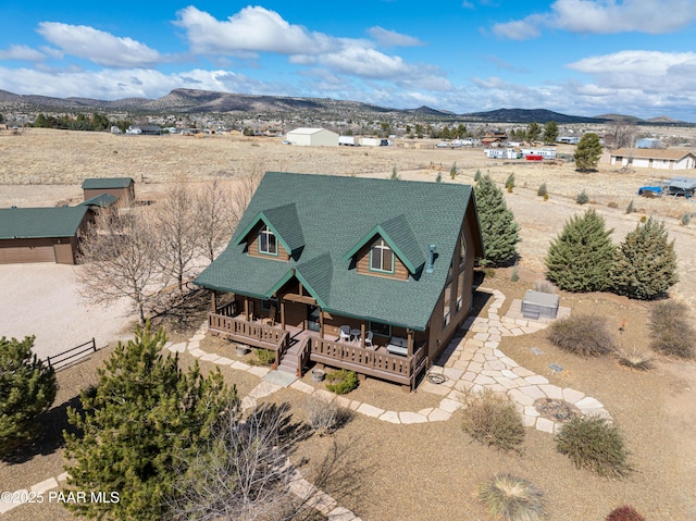view of front of house with a porch, roof with shingles, fence, and a mountain view