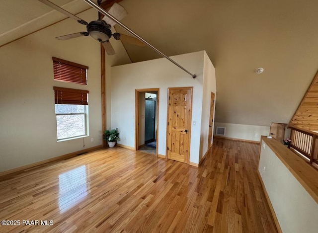 interior space with visible vents, light wood-style flooring, ceiling fan, high vaulted ceiling, and baseboards