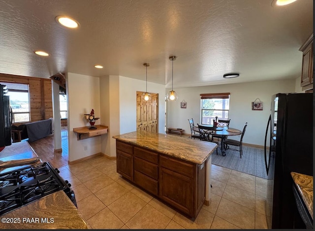 kitchen featuring light tile patterned floors, gas range oven, a textured ceiling, and freestanding refrigerator