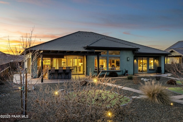 back house at dusk with a patio area