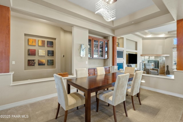 dining space with carpet, a tray ceiling, and a notable chandelier