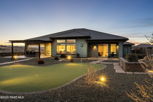 back house at dusk featuring a patio area