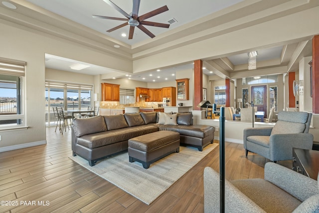 living room with a raised ceiling and ceiling fan