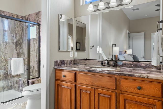 bathroom featuring toilet, a shower with door, and vanity