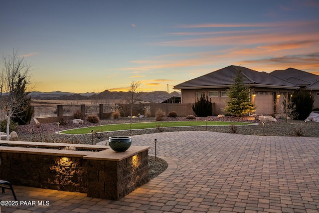 patio terrace at dusk with a garage and a mountain view