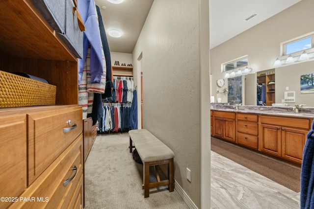 walk in closet with sink and light colored carpet