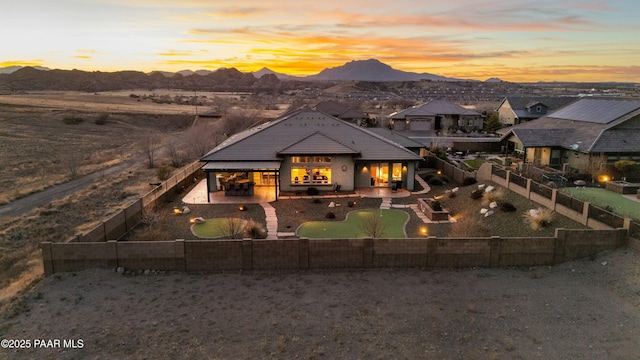 back house at dusk featuring a patio area and a mountain view