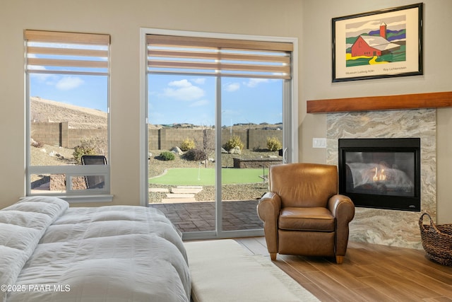 bedroom with a tiled fireplace, access to exterior, and hardwood / wood-style floors