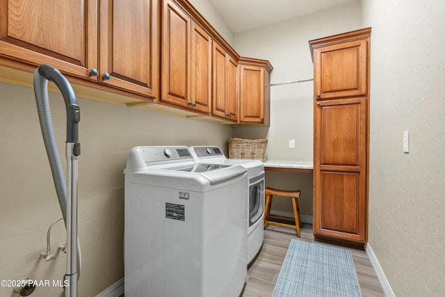 washroom with light wood-type flooring, cabinets, and washing machine and clothes dryer