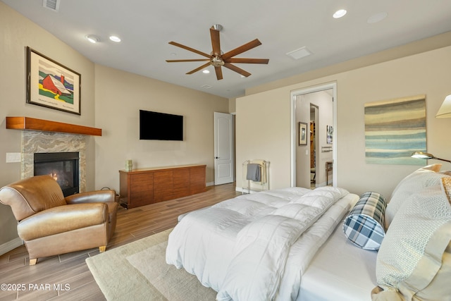 bedroom with a tiled fireplace and ceiling fan