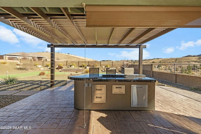 view of patio with an outdoor kitchen, a mountain view, and a pergola