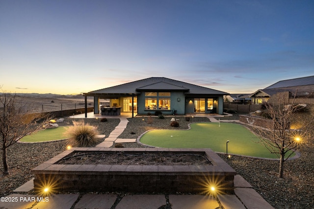 back house at dusk with a patio area