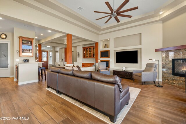 living room with a fireplace, ceiling fan, and built in features