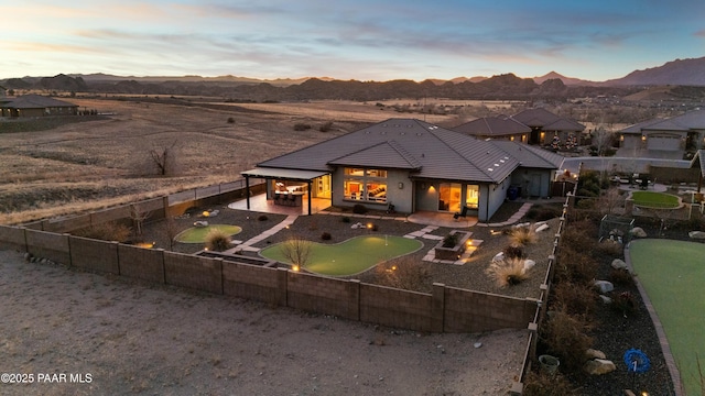 back house at dusk featuring a patio and a mountain view