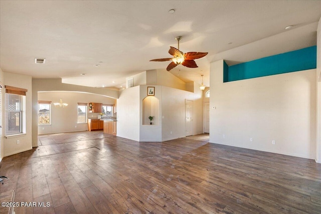 unfurnished living room featuring ceiling fan with notable chandelier, dark hardwood / wood-style floors, and lofted ceiling