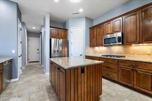 904 Daybreak Dr, Prescott, AZ 86303 - kitchen with appliances with stainless steel finishes, decorative backsplash, a kitchen island, baseboards, and light stone counters