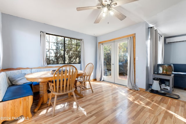 dining space featuring a wall mounted air conditioner, ceiling fan, light hardwood / wood-style flooring, and french doors