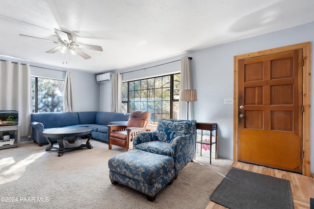 living room featuring a wall mounted air conditioner, ceiling fan, and a wealth of natural light