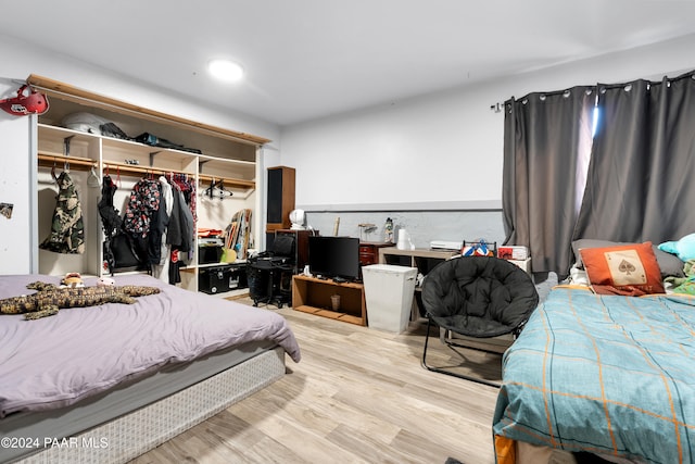 bedroom with light hardwood / wood-style floors and a closet