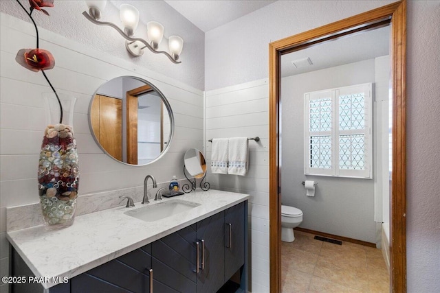 bathroom with toilet, vanity, visible vents, and baseboards