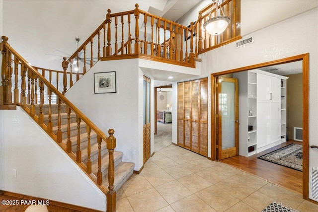 staircase with tile patterned flooring, visible vents, and a towering ceiling