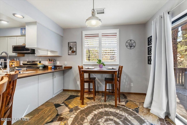 kitchen featuring stainless steel appliances, dark countertops, visible vents, and baseboards