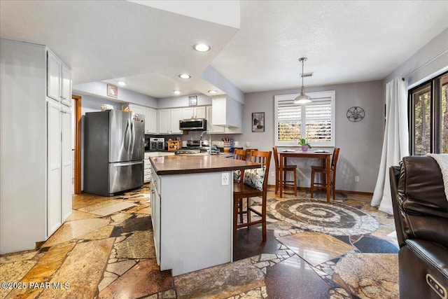 kitchen with plenty of natural light, stainless steel appliances, stone tile flooring, and a kitchen breakfast bar