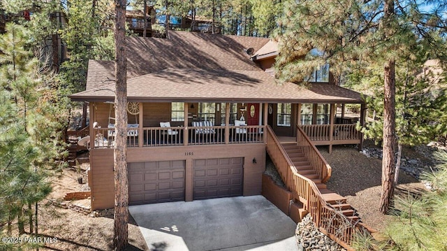 chalet / cabin with a garage, a shingled roof, stairway, and concrete driveway