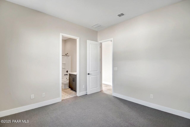 unfurnished bedroom featuring light carpet and ensuite bathroom