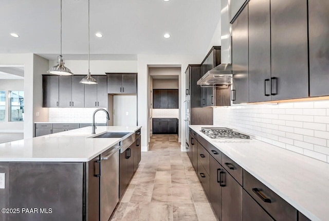 kitchen with stainless steel appliances, sink, a center island with sink, and decorative light fixtures