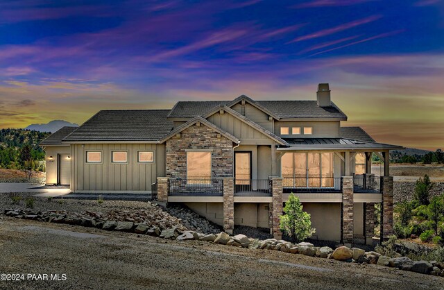 5939 W Cedron Cir, Prescott, AZ 86305 - view of front facade featuring stone siding, a balcony, metal roof, a chimney, and a standing seam roof