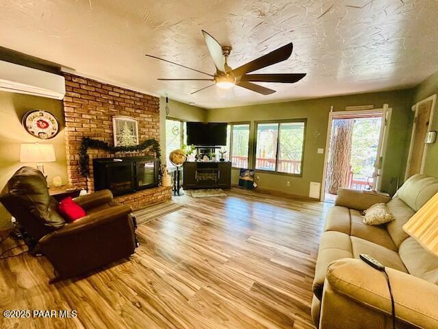 1696 W Linger Ln, Prescott, AZ 86303 - living area featuring a brick fireplace, ceiling fan, wood finished floors, and a wall unit AC