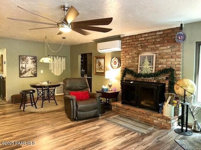 1696 W Linger Ln, Prescott, AZ 86303 - living room with a wall mounted AC, a ceiling fan, wood finished floors, and a fireplace