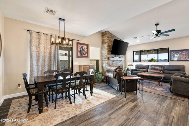 dining room featuring hardwood / wood-style flooring, a fireplace, and vaulted ceiling