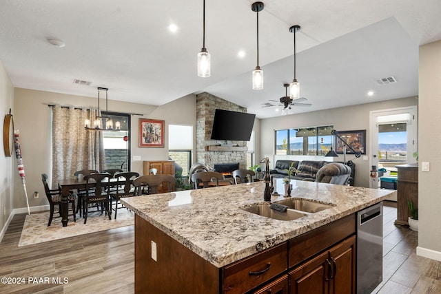 kitchen with sink, hardwood / wood-style floors, lofted ceiling, a kitchen island with sink, and ceiling fan with notable chandelier