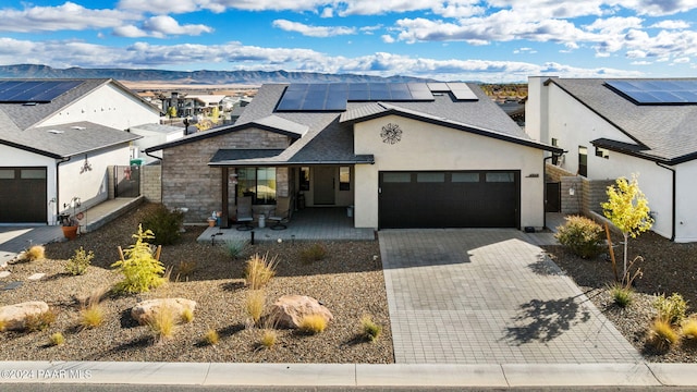 view of front facade featuring solar panels, a mountain view, covered porch, and a garage