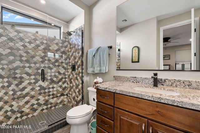 bathroom featuring ceiling fan, a shower with door, vanity, and toilet