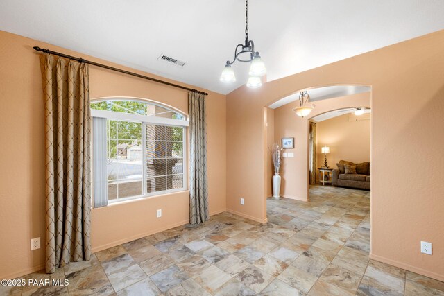 unfurnished room with arched walkways, a chandelier, baseboards, and stone finish flooring