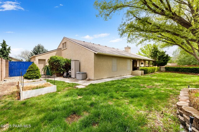 view of home's exterior featuring a chimney, a garden, and stucco siding